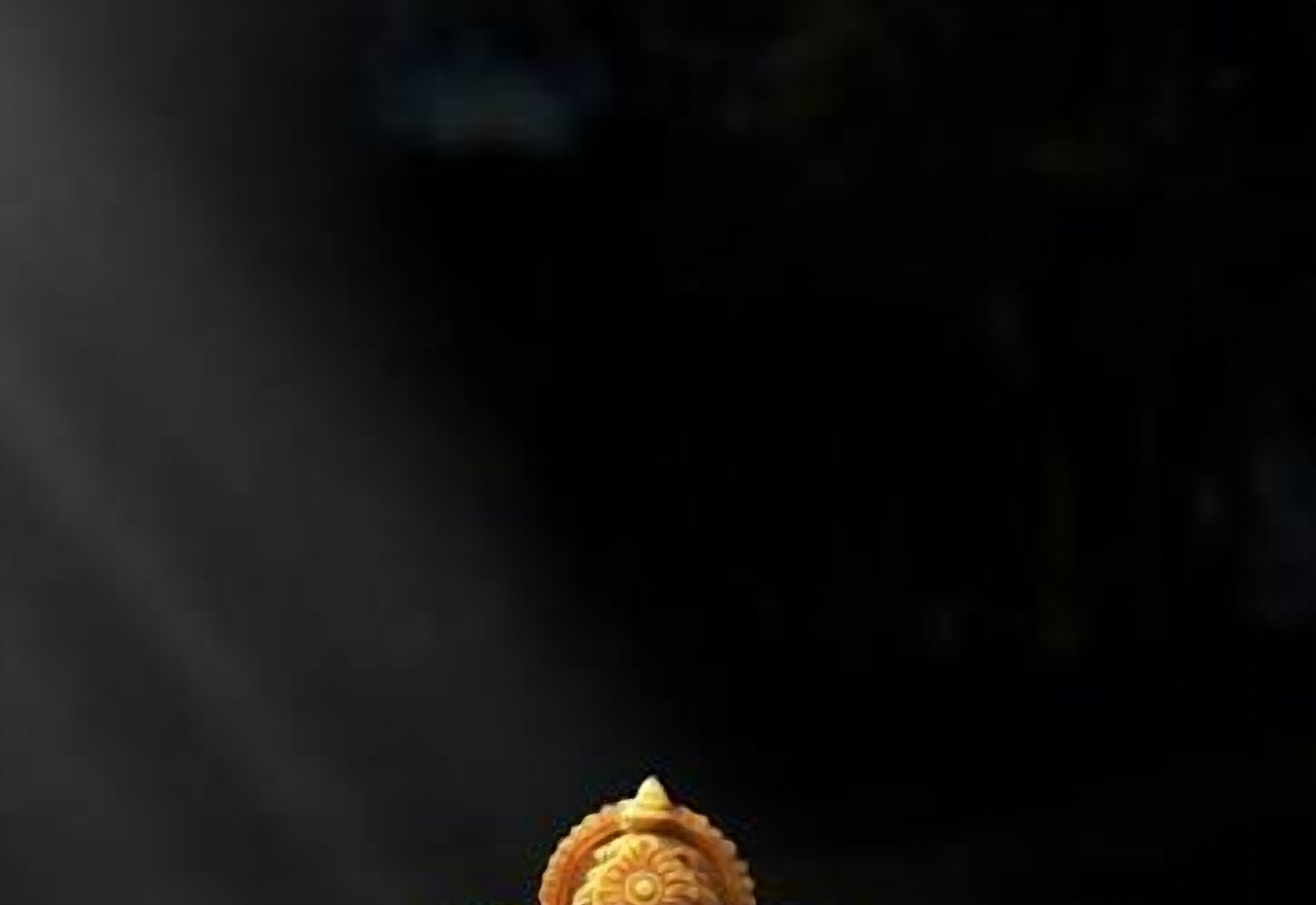 A small golden Ganpati idol resting on a green leaf